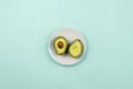 Flatlay with cut avocado on white plate on pastel background