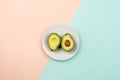 Flatlay with cut avocado on white plate on pastel background