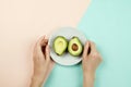 Flatlay with cut avocado on white plate and woman`s hands