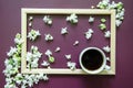 Flatlay dark purple background with small white lilac flowers? white coffee cup on textured background inside a wooden frame Royalty Free Stock Photo