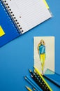 Flatlay empty space dark blue cover Stripe Notepad on a blue background vertical fashion sketch of the model