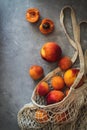 Flatlay with fresh ripen apricots in a market sack on a grey background