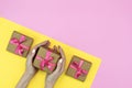 Flatlay of Gift present boxes with pink ribbon, orchid flowers on pink yellow background with female hands holding gift Royalty Free Stock Photo