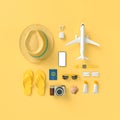 Flatlay with hat with sun glasses, t suitcase, slippers, hat, suntan cream, phone and camera on yellow minimal style background.