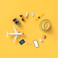 Flatlay with hat with sun glasses, t suitcase, slippers, hat, suntan cream, phone and camera on yellow minimal style background.