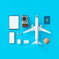 Flatlay with hat with sun glasses, toy plane, slippers, hat, suntan cream, phone and camera on blue minimal style background.