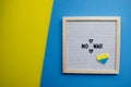 Flatlay horizontal composition with framed letter board and embroidered patriotic ukrainian heart, yellow and blue