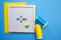 Flatlay horizontal composition with framed letter board and embroidered patriotic ukrainian heart, yellow and blue threads