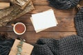 Flatlay hygge style composition with fashion women knitted scarf, letter, blank paper card, mug of tea, present, firewood on