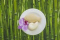 Flatlay image with orchid flower, fish and shell shaped soap on green bamboo background