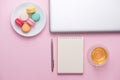 Flatlay of laptop, cake macaron and cup of tea on pink table. Be Royalty Free Stock Photo