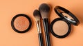 Flatlay of Makeup Essentials on Peach Background with Brushes and Powder Compacts in Studio Setting Royalty Free Stock Photo