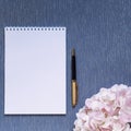 Flatlay with mockup. Notepad clean with a blank page for writing text, pen, pink hydrangea flowers on a blue background