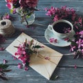 Flatlay with pink spring flowers, a cup of coffee, threads, an envelope. Top view. Royalty Free Stock Photo