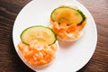Flatlay, sandwich with red fish and cucumber on a white plate. Salted salmon on crispy rice bread on a wooden background