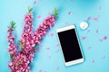 Flatlay with smartphone mock up and flowers. Floral pattern at blue background. Top view. Flowers composition. Spring background