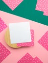 Flatlay square note sheets on wooden base,green diagonal paper,corners of pink paper with white polka dots,copy space