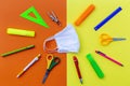 Flatlay with student accessories as ruler, pencil sharpener, scissors around medical face mask. Royalty Free Stock Photo