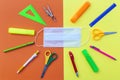 Flatlay with student accessories as ruler, pencil sharpener, scissors around medical face mask. Royalty Free Stock Photo