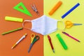 Flatlay with student accessories as ruler, pencil sharpener, scissors around medical face mask. Royalty Free Stock Photo