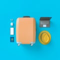 Flatlay with suitcase with sun glasses, slippers, hat, suntan cream, phone and camera on blue minimal style background. Travel