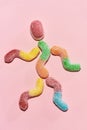 Flatlay of tasty colorful sour sugar coated gummy worm candies lying in the shape of little human isolated over pastel Royalty Free Stock Photo