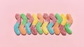 Flatlay of tasty colorful sour sugar coated gummy worms lying vertically isolated over pastel pink background Royalty Free Stock Photo