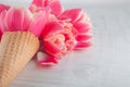 Flatlay waffle sweet ice cream cone with pink tulips blossom flowers over white wood background