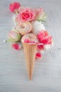 Flatlay waffle sweet ice cream cone with pink tulips and roses blossom flowers over white wood background, top view Royalty Free Stock Photo