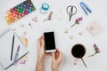 Flatlay of watercolors, brushes, sketchbook with blank page, cup of tea, smartphone with black screen