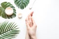 Flatlay. Woman putting nutritious cream on her hands on white background among jar of cosmetic cream, leaf palm branch Royalty Free Stock Photo