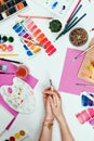 Woman`s hands holding brush, pallets, pencils, watercolors, colored paper and other stationary supplies Royalty Free Stock Photo