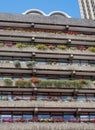 Flats built in post-war Brutalist style architecture at The Barbican in the City of London UK, with colourful flowers on the balco Royalty Free Stock Photo