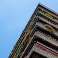 Flats built in post-war Brutalist style architecture at The Barbican in the City of London UK, with colourful flowers on the balco Royalty Free Stock Photo