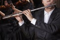 Flautist holding and playing the flute during a performance, close-up