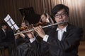 Flautist holding and playing the flute during a performance, looking at the camera Royalty Free Stock Photo