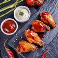 Flavor Fusion: Fried Chicken Wings Dressed in Sauces and Seasonings, Set Against Black Slate