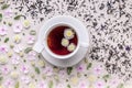 Flavored herbal tea in a white ceramic cup with a saucer. Floral pattern on a beige background. Flower tea concept. Tea bag. Top Royalty Free Stock Photo
