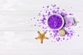 Flavored purple sea salt crystals for spa with violet flower, starfish and stones on white