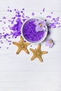 Flavored purple sea salt crystals with violet flower and starfishes on white