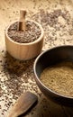 Flax seed coarse ground flour in a clay bowl with linseed wooden bowl nearby on rustic wood