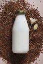 flax seed milk in bottle on beige background with plant. copy space. Royalty Free Stock Photo