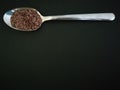 Flax seeds in the spoon on black background, vintage color tone