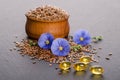 Flax seeds in the wooden bowl, beauty flower and oil in caps Royalty Free Stock Photo