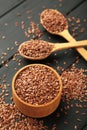 Flax seeds on wooden bowl and spoon on black background