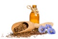 Flax seeds in the wooden scoop, bottle with oil and flowers Royalty Free Stock Photo