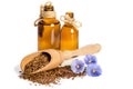 Flax seeds in the wooden scoop, bottles with oil and beauty flowers Royalty Free Stock Photo