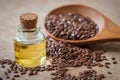 Flaxseed oil in bottle and brown flax seeds on wooden spoon