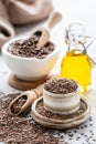 Flaxseed oil in a bottle and ceramic bowl with brown flax seeds and wooden spoon on a white background. vertical Royalty Free Stock Photo