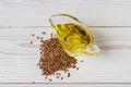 Flaxseed oil in a glass gravy boat. Flax seeds on a white background